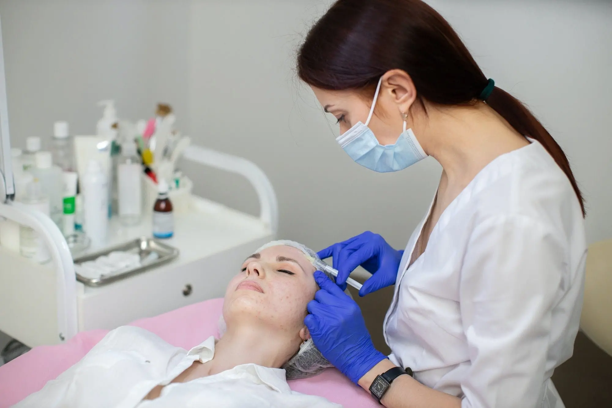 Female cosmetologist makes rejuvenating botox anti wrinkle injections on the face