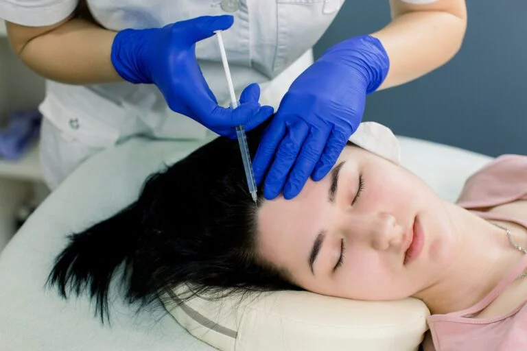 Hair mesotherapy or hair transplant: a beautician doctor makes injections in the head of a woman for